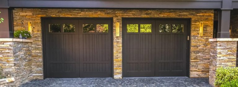 Two modern, dark-colored garage doors with vertical paneling and small windows at the top