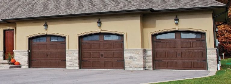 Three brown carriage-style garage doors with top windows and decorative hardware on a home in St. Charles