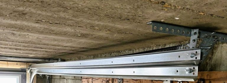 Garage door opener rail and torsion hardware above a door inside a St. Charles garage