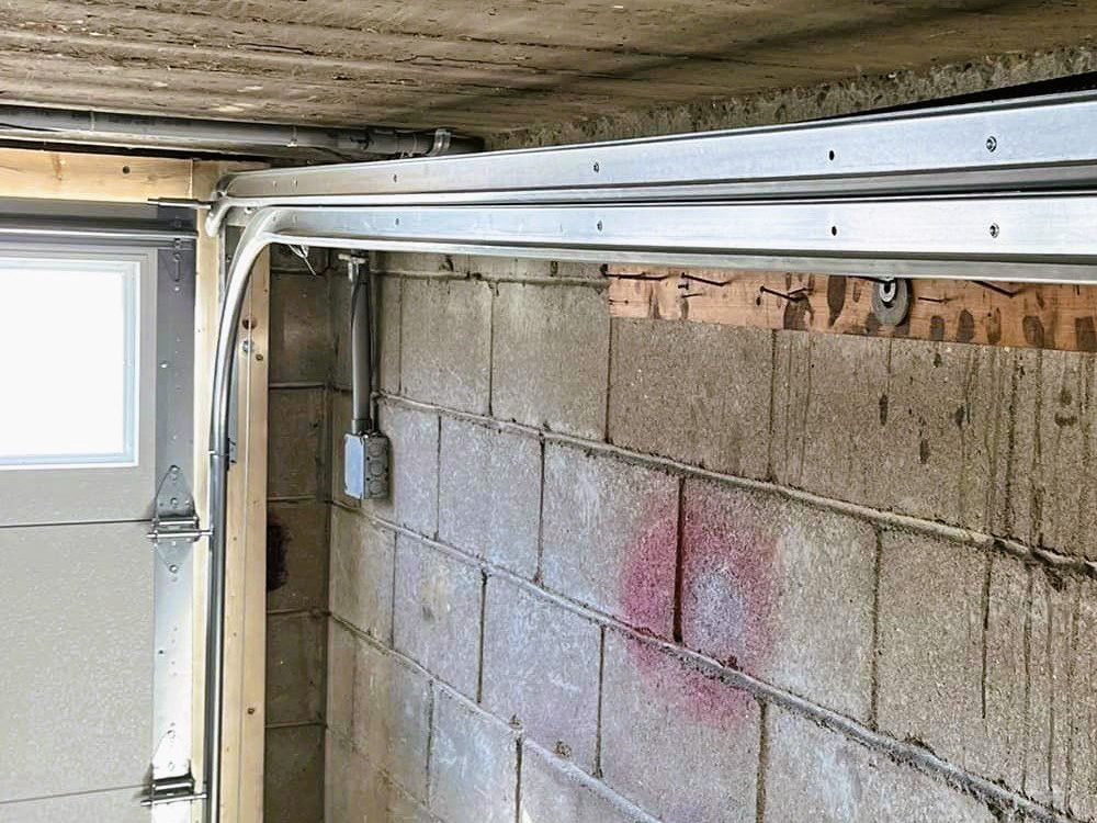 The vertical track and curved section of a garage door track beside the door, where rollers most often leave the rail