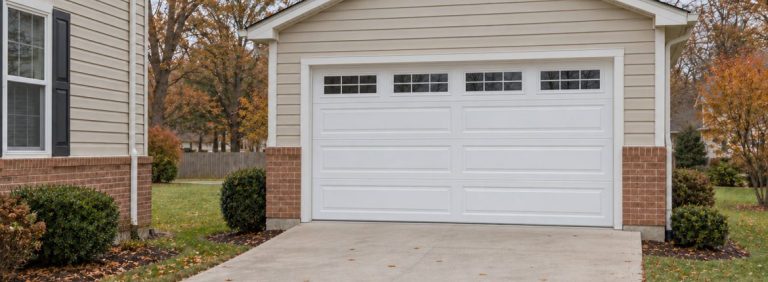 A closed white sectional garage door on a house, seen from the driveway on an autumn afternoon